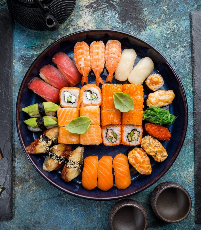 Set of sushi and maki with soy sauce over blue stone background. Top view with copy space